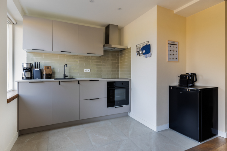 Moderne keuken met oven, kookplaat en koffiezetapparaat in vakantiehuis Boszicht 16a Schiermonnikoog