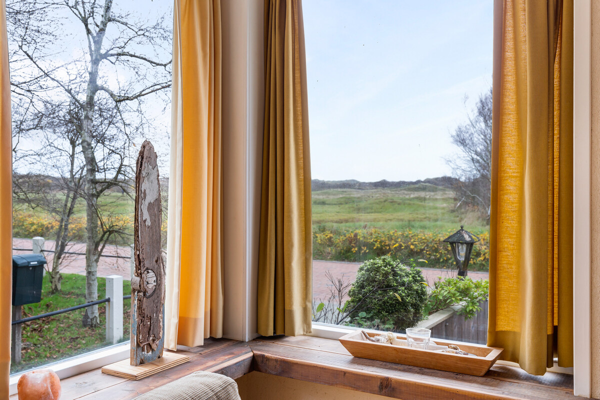 Eethoek met grote ramen en uitzicht op duinen bij vakantiehuis Boszicht 16a Schiermonnikoog